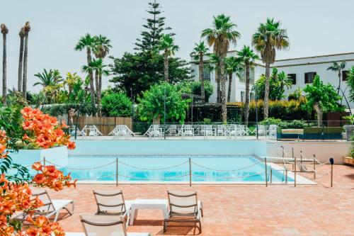 a pool at a hotel with chairs and palm trees at Villa Favorita Hotel & Events in Marsala