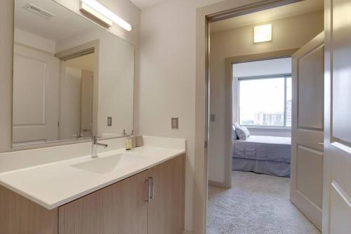 a bathroom with a sink and a mirror and a bed at Stunning City view - Condo at Crystal City with Rooftop in Arlington