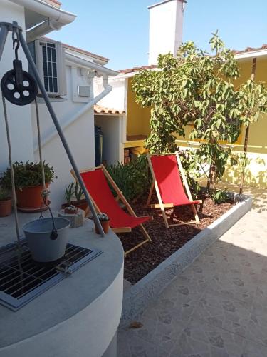 two red chairs sitting in a yard next to a house at Casa do Poço in Quinta do Anjo