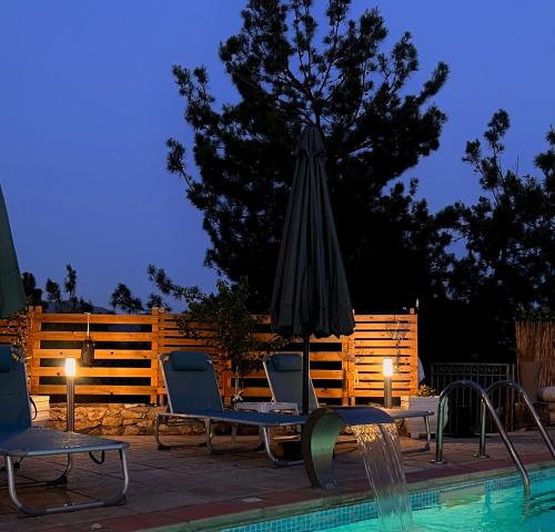 a pool with chairs and an umbrella next to a swimming pool at Villa Kastro Elassona in Elassona