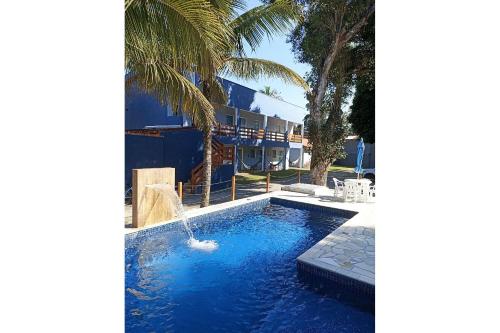 - une piscine avec une fontaine en face d'une maison dans l'établissement Maresias Flat's Unidade II, à Maresias