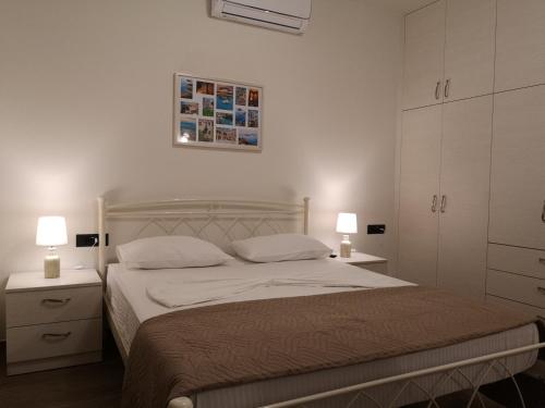 a bedroom with a bed with two night stands and two lamps at SUNNY HOLIDAYS APARTMENT in Kremasti