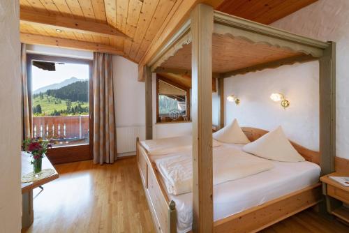 a bedroom with a bed and a large window at Alpenhotel Wanderniki in Liesing