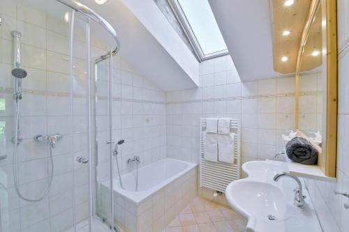 a bathroom with a shower and a tub and a sink at Alpenhotel Wanderniki in Liesing