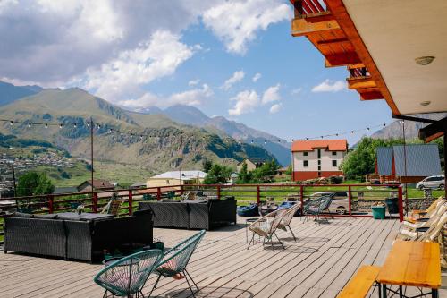 una terraza con sillas y mesas con montañas en el fondo en Alpenhaus Kazbegi Hotel & Restaurant, en Kazbegi