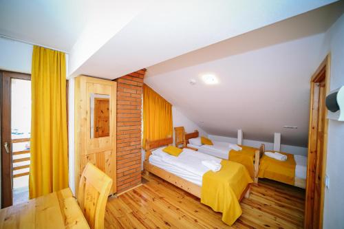 a hotel room with two beds and a table at Alpenhaus Kazbegi Hotel & Restaurant in Stepantsminda
