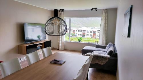 a living room with a dining room table and a television at Apartment with Amazing Mountain View in Bolungarvík