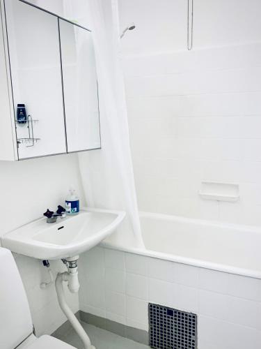 biała łazienka z umywalką i wanną w obiekcie Gamla Järnvägsgatan 6 w mieście Bollnäs