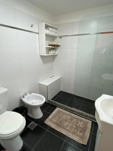 a white bathroom with a toilet and a sink at Departamento Diag Buenos Aires 55 in Capilla del Monte