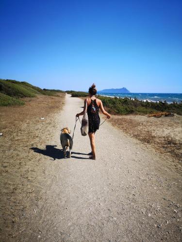 a woman walking a dog on a gravel road at Eco House San Michele in San Michele