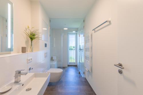 Baño blanco con 2 lavabos y aseo en Ferienwohnung "Die Komfortzone" direkt am Nordseedeich mit Blick auf den See, en Nordstrand