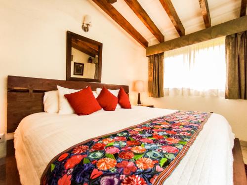 a bedroom with a large bed with red pillows at La Buena Vibra Retreat and Spa Hotel in Tepoztlán