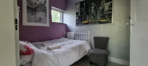 a bedroom with a white bed and a chair at Lovely 1 bedroom apartment with garden in Amsterdam