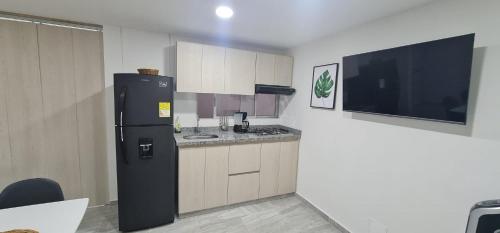 a kitchen with a black refrigerator and a tv at Hermoso Apartamento Entero - Parqueadero - Ibague - Roble in Ibagué