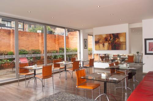 a restaurant with tables and chairs and windows at Suites Casa 95 in Bogotá
