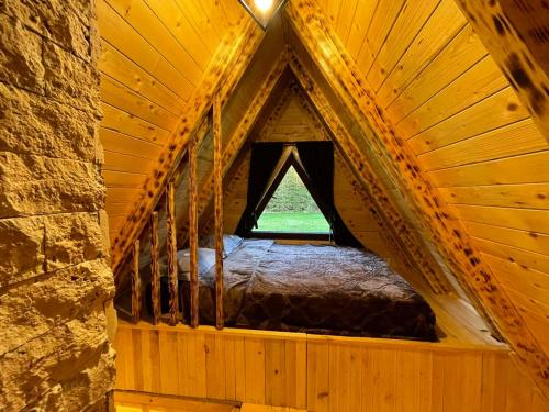 a bed in a wooden room with a window at Rajska suma in Žabljak