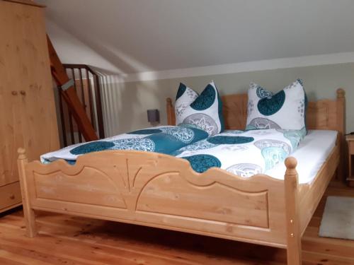 a wooden bed with blue and white pillows on it at Modern holiday home on the outskirts of Saxon Switzerland with covered terrace in Hohnstein