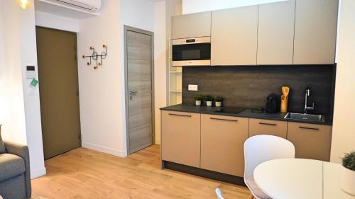 une cuisine avec des armoires blanches et une table dans une pièce dans l'établissement Proche Carlton & Croisette, Appartement 103, à Cannes