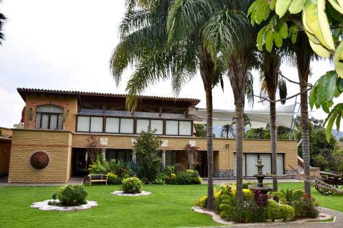 a house with palm trees in front of it at La Buena Vibra Retreat and Spa Hotel in Tepoztlán