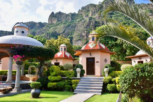 a church in a garden with a mountain in the background at La Buena Vibra Retreat and Spa Hotel in Tepoztlán