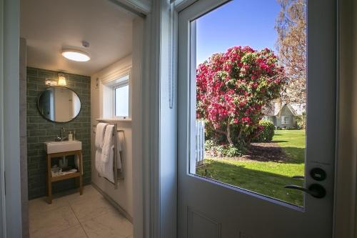 a bathroom door with a view of a tree with pink flowers at The Vicarage Geraldine in Geraldine