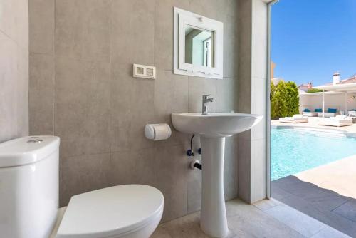 a bathroom with a toilet and a sink next to a swimming pool at Ohana2 Luxury Villa in Málaga