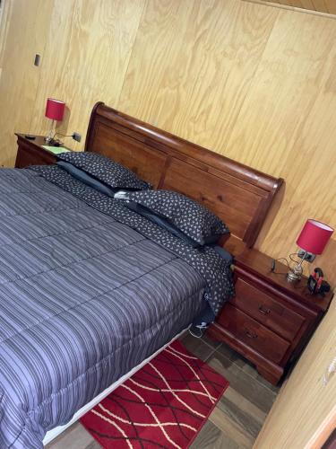 a bedroom with a bed with a wooden headboard and two lamps at Cabaña Recinto Valle Las Trancas in Recinto