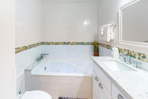 a white bathroom with a tub and a sink at Isle of View Too in Mexico Beach