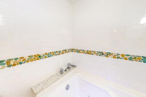 a bathroom with a bath tub with a tile border at Isle of View Too in Mexico Beach