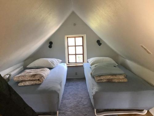 2 camas num quarto no sótão com uma janela em Holiday home Allinge XXV em Allinge