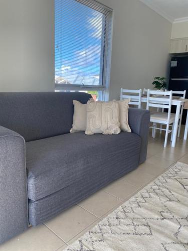 a blue couch with two pillows on it in a living room at Modern Luxury 1 Bedroom Apartment - Walk to the shops! Free Wifi in Clarkson