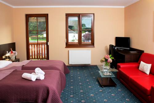 a hotel room with two beds and a red couch at Sportpenzion Pohoda in Pilsen
