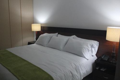 a bedroom with a white bed with two lamps at Hotel Palonegro in Bucaramanga