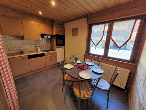 une cuisine avec une table et des chaises dans une pièce dans l'établissement Appartement cosy aux Gets, idéal pour la famille, proche pistes et commerces - FR-1-598-104, aux Gets