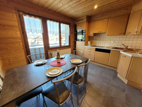 une cuisine avec une table et des chaises dans une pièce dans l'établissement Appartement centre-station avec balcons, 3 étoiles, proche commerces et pistes, 5-6 pers. - FR-1-598-106, aux Gets