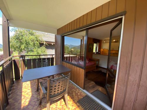d'un balcon avec une table en bois et une fenêtre en verre. dans l'établissement La Clusaz - 3 pièces - Proche pistes - Garage - Animaux admis - FR-1-437-95, à La Clusaz