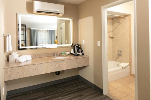 a bathroom with a sink and a mirror and a tub at Waypoint Hotel in Bend