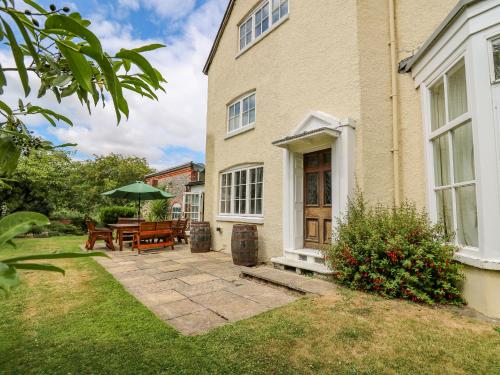 a house with a patio with a table and an umbrella at The Laurels in Bishops Castle