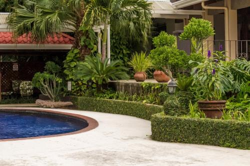 a garden with a swimming pool and many plants at La Riviera Hotel in San Antonio