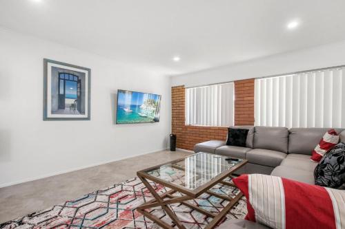a living room with a couch and a glass table at Bell Street 36 Dicky Beach in Caloundra
