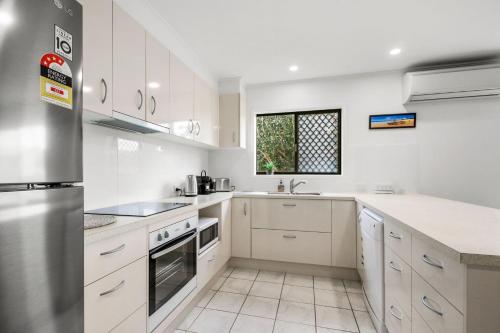 a white kitchen with white cabinets and a window at Bell Street 36 Dicky Beach in Caloundra