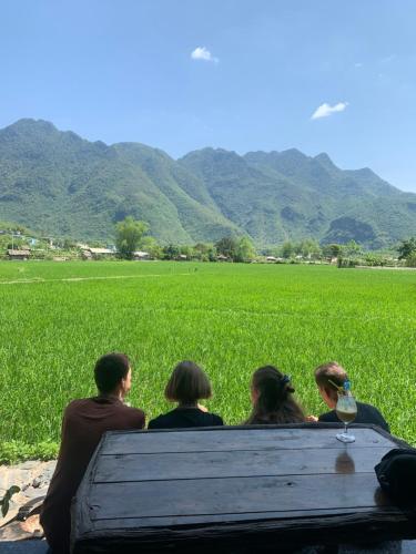 a group of people sitting on a bench looking at a field at Mai Chau Countryside Homestay in Mai Chau