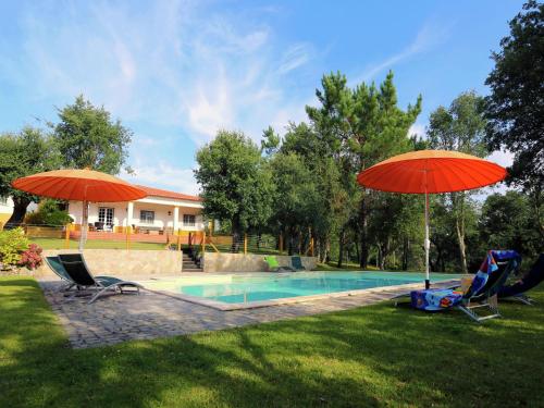 a swimming pool with two umbrellas and two chairs and a pool at Luxurious Villa in Caldas da Rainha with Swimming Pool in Salir de Matos