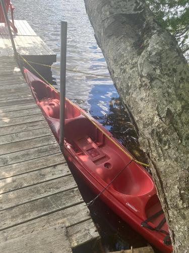 a red boat tied to a dock next to the water at Le petit chalet sur le lac in Sainte-Marguerite