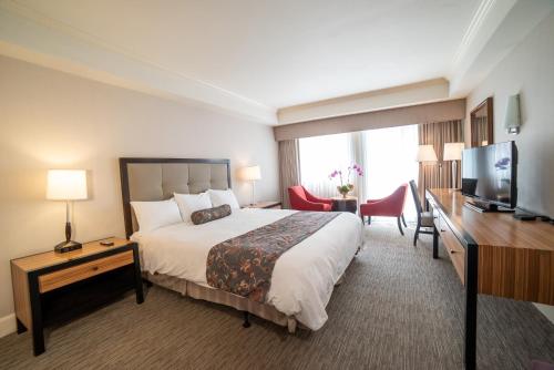 ein Hotelzimmer mit einem Bett und einem Flachbild-TV in der Unterkunft Oxford Palace Hotel in Los Angeles