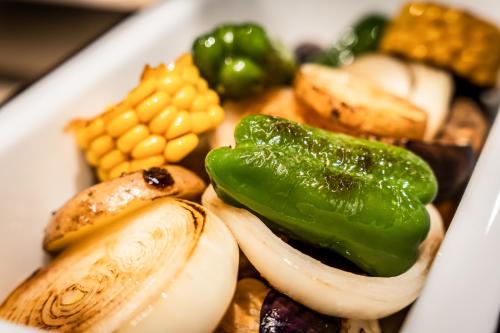 a white plate of food with vegetables and corn at Higashikawa Asahidake Onsen Hotel Bear Monte in Higashikawa