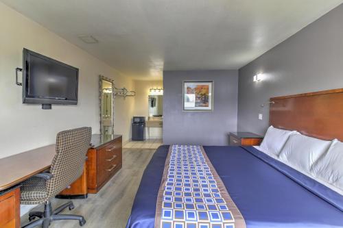 a room with a bed and a desk and a tv at Budget Lodge Churchland in Chesapeake