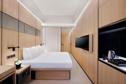 a hotel room with a bed and a flat screen tv at Harbour Plaza Metropolitan Shanghai in Shanghai