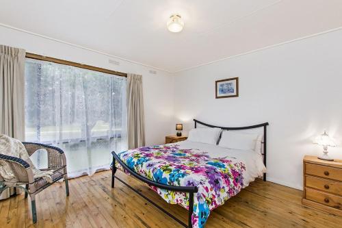 a bedroom with a bed and a window and a chair at Bindi in Port Fairy