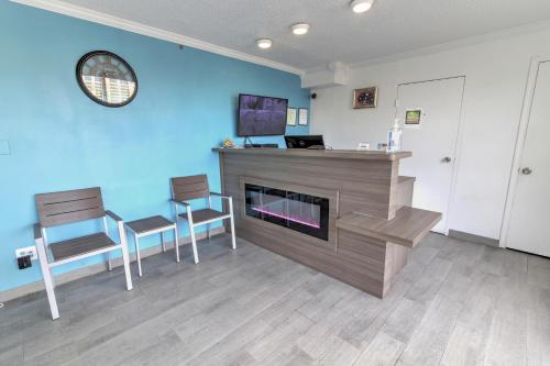 a living room with a fireplace and two chairs at White Marlin Inn - Virginia Beach in Virginia Beach